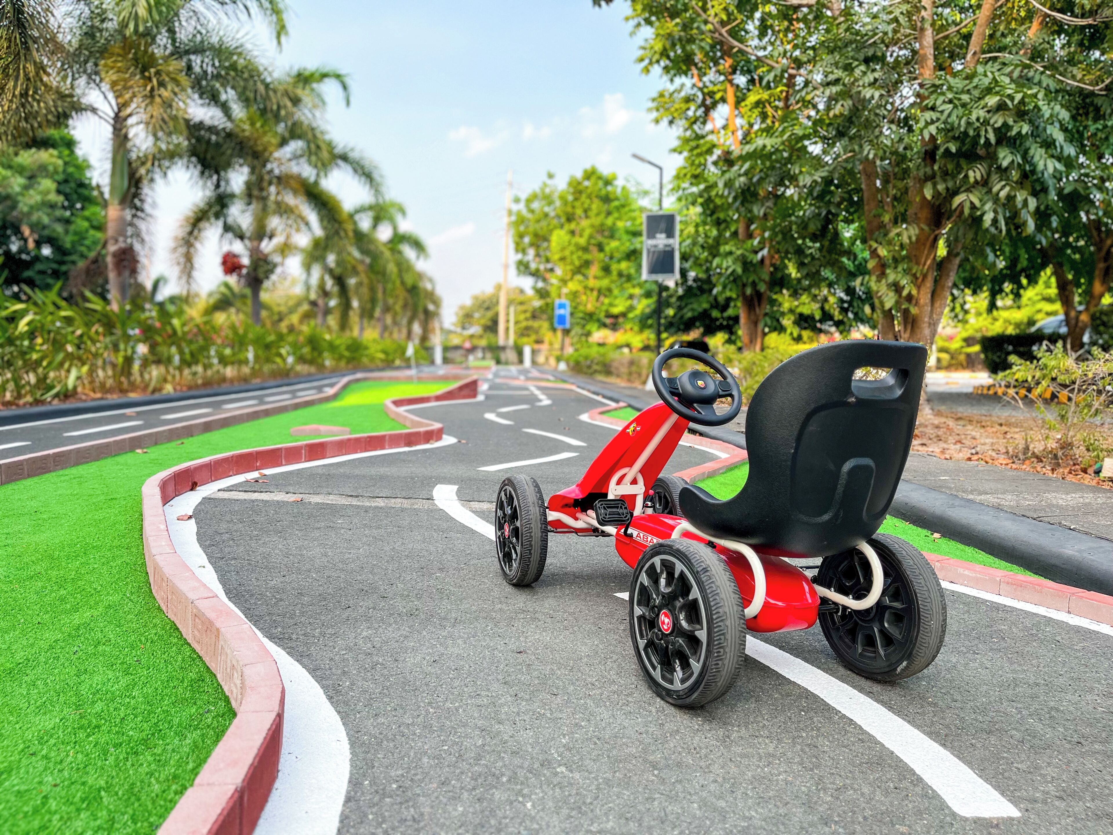 A go-kart on a road with green curbs and palm trees.