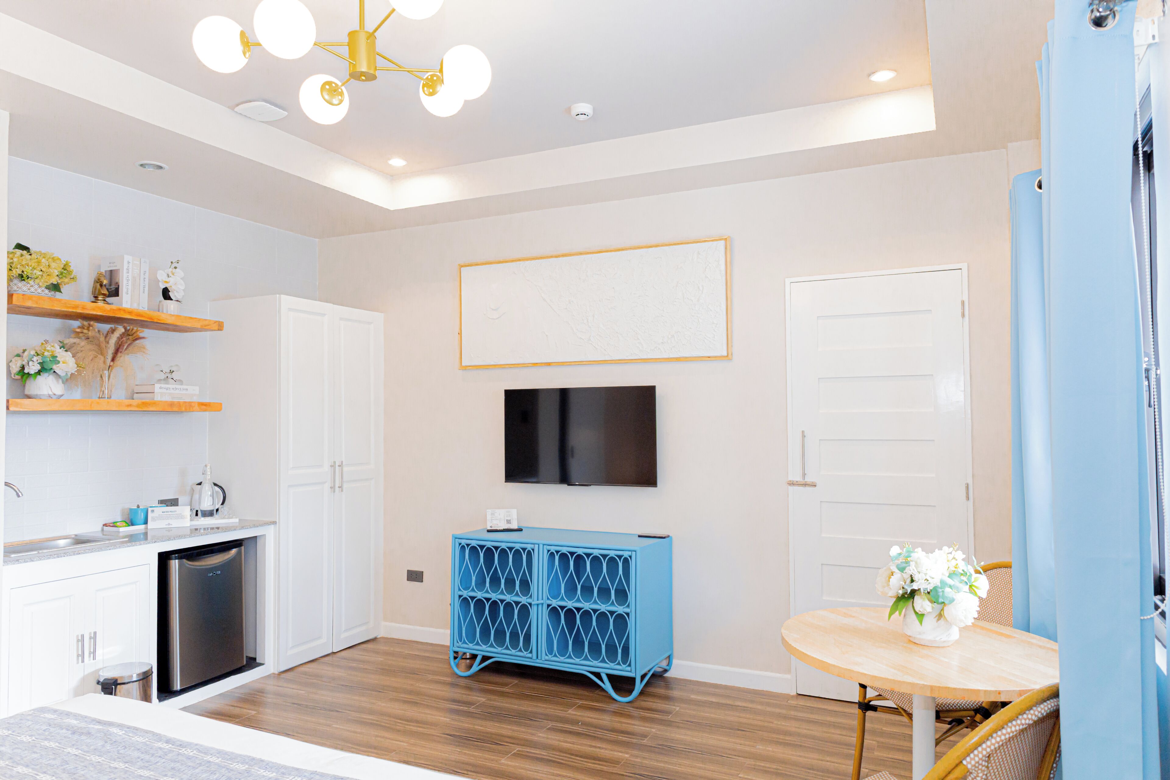 A modern kitchen with white cabinetry, a built-in dishwasher, and a blue storage unit.