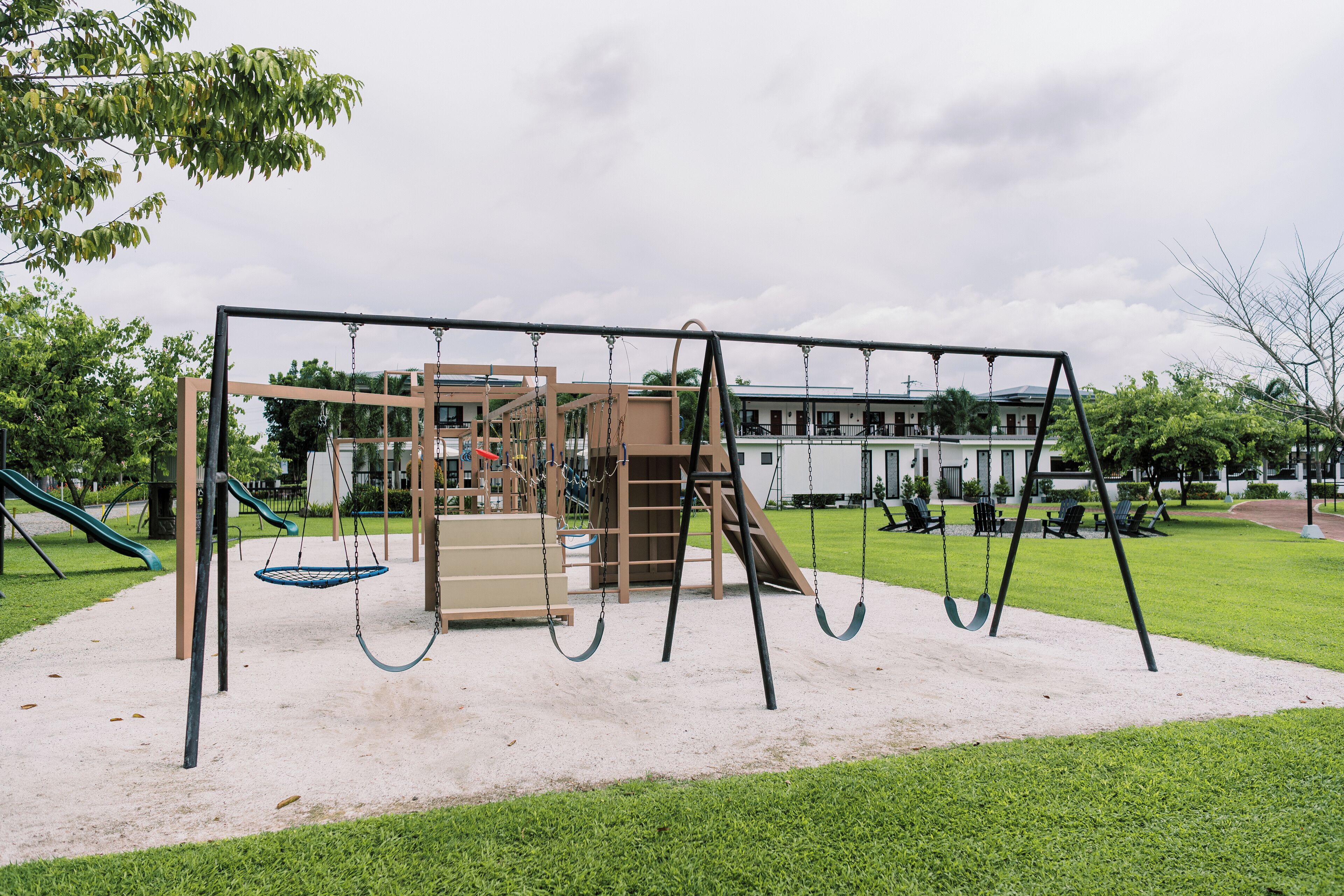 Un parque infantil con columpios, un tobogán y una estructura para escalar.