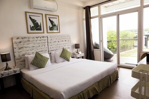 Ein Hotelzimmer mit einem großen Bett, zwei Nachttischen, einem Schreibtisch und einem Balkon mit Blick.