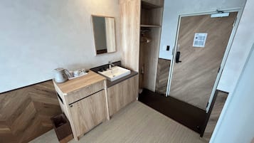 A modern bathroom with a wooden vanity, a sink, and a mirror. There is a door with a handle and a small sign on it.