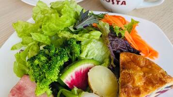 Un plato de comida con una porción de quiche, una taza de café y un pequeño plato de pan.