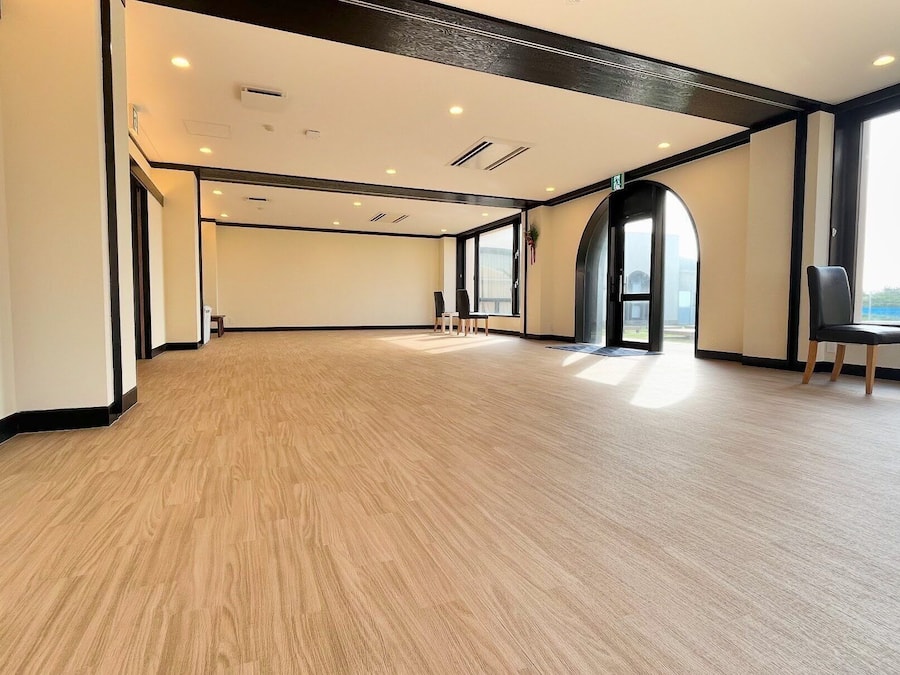 Une pièce spacieuse dotée d’un plancher en bois, de grandes fenêtres et d’une porte à cadre noir.