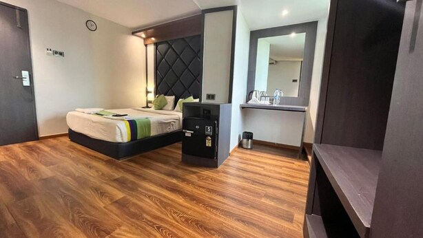 Une chambre d’hôtel moderne avec un grand lit, un petit bureau, un miroir et un plancher en bois.
