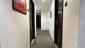 Un couloir avec des portes de chaque côté, un sol recouvert de moquette et un luminaire au plafond.