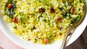 Un bol de riz jaune garni de cacahuètes, de coriandre et d’un quartier de citron vert.