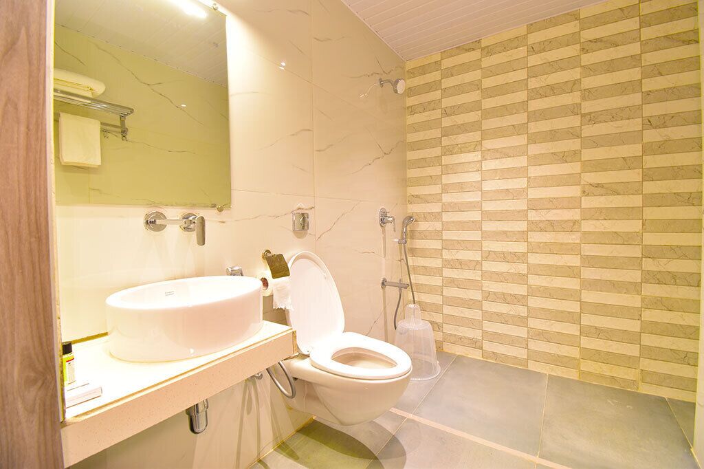 A modern bathroom with a white sink, a toilet, and a shower.