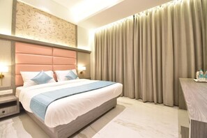 A modern hotel room with a large bed, a headboard, a nightstand, a desk, and a curtain. - La DHALIA By Glitz Hotels (Thane)