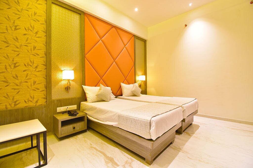 Una habitación de hotel con una cama grande, dos lámparas de noche, una mesita de noche y una pequeña mesa.