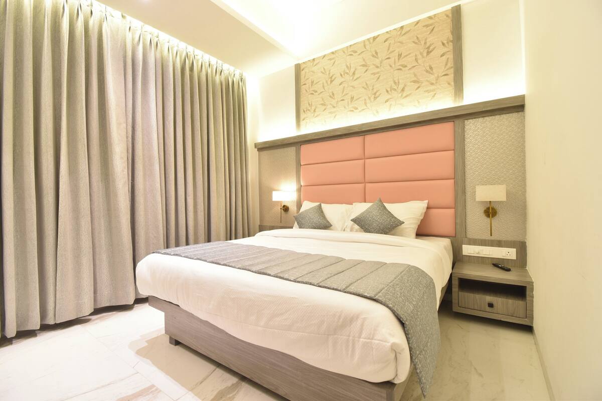 Una camera d'albergo ordinata con un letto grande, un comodino e un tavolino.