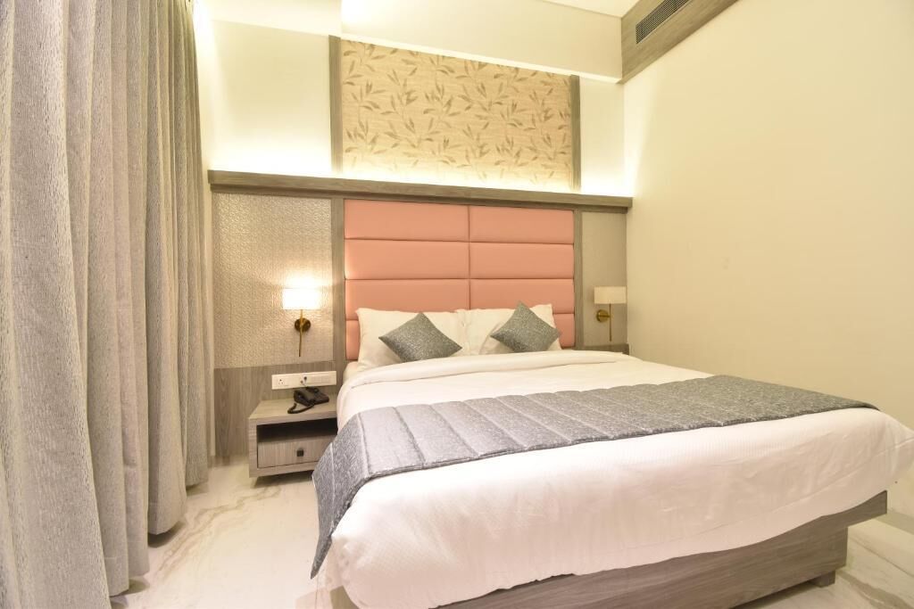 Una camera d'albergo con un letto grande, un comodino, una lampada e una tenda.