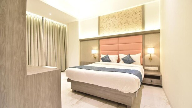 Une chambre d’hôtel moderne avec un grand lit, une commode en bois et un panneau décoratif mural.