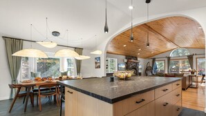 Cucina spaziosa con isola grande, soffitto in legno e luci a sospensione.