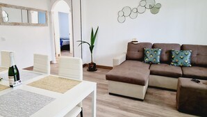 A modern living room with a brown sofa, a white table with a bottle, and a mirror on the wall. - Los Cristianos, 3 Bedrooms & WiFi Free (LOS CRISTIANOS)