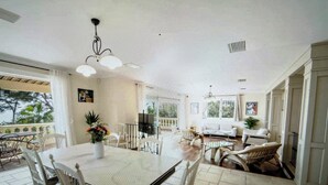 A spacious dining area with a large table and chairs, a ceiling fan, and a view of the outdoors.