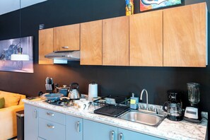 A modern kitchen with wooden cabinets, a stainless steel sink, a coffee maker, and a blender.