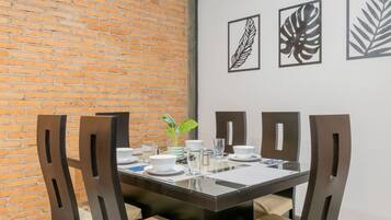 A dining area with a brick wall, a glass table, and four chairs.