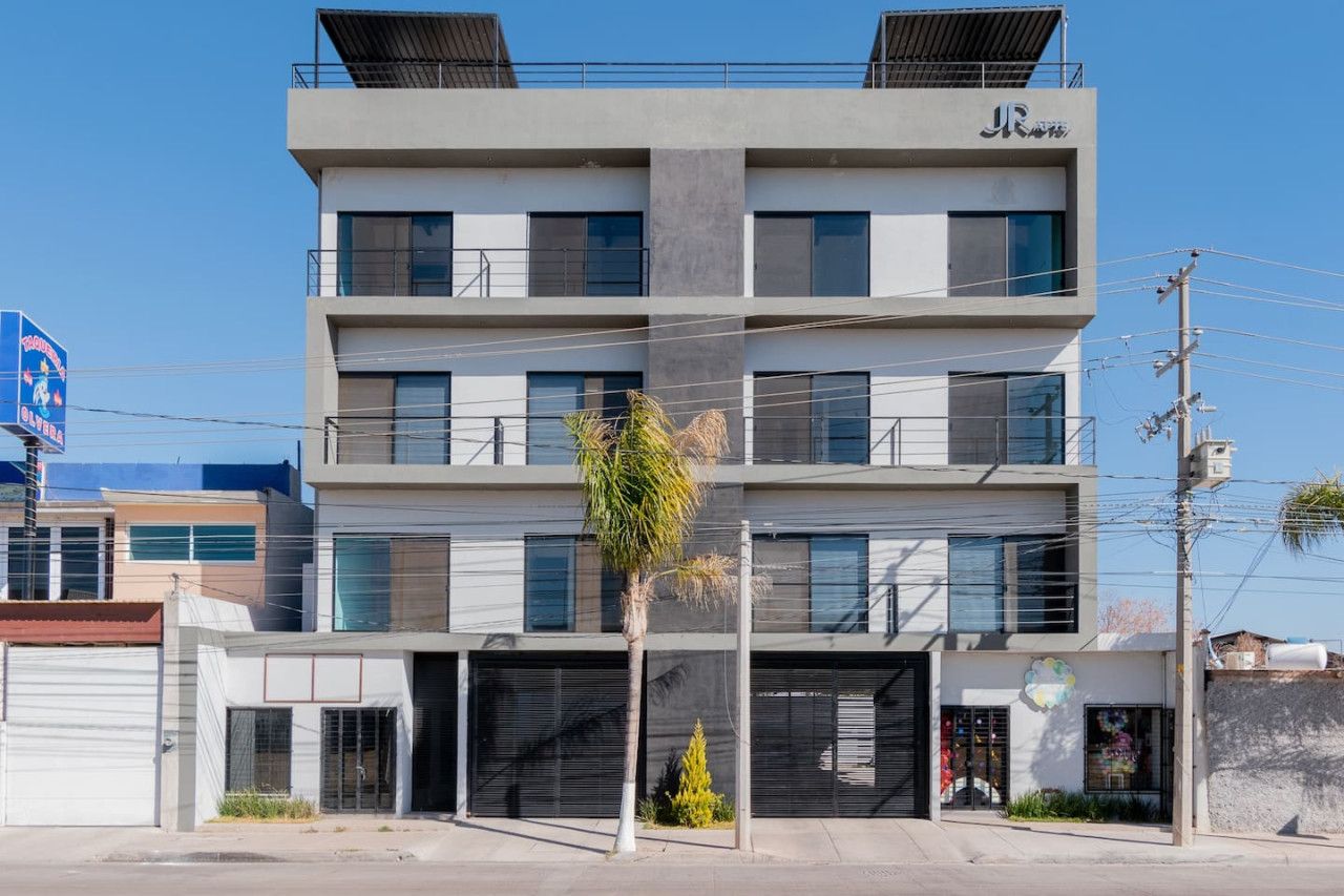 A multi-story building with a modern design, featuring balconies on the upper floors and a ground-level entrance.