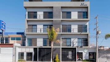 A multi-story building with a modern design, featuring balconies on the upper floors and a ground-level entrance.
