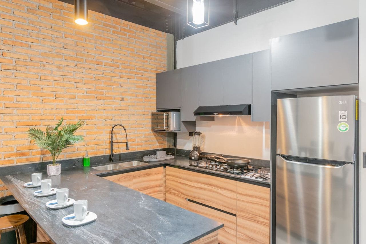 A modern kitchen with a brick wall, stainless steel appliances, and a black countertop.