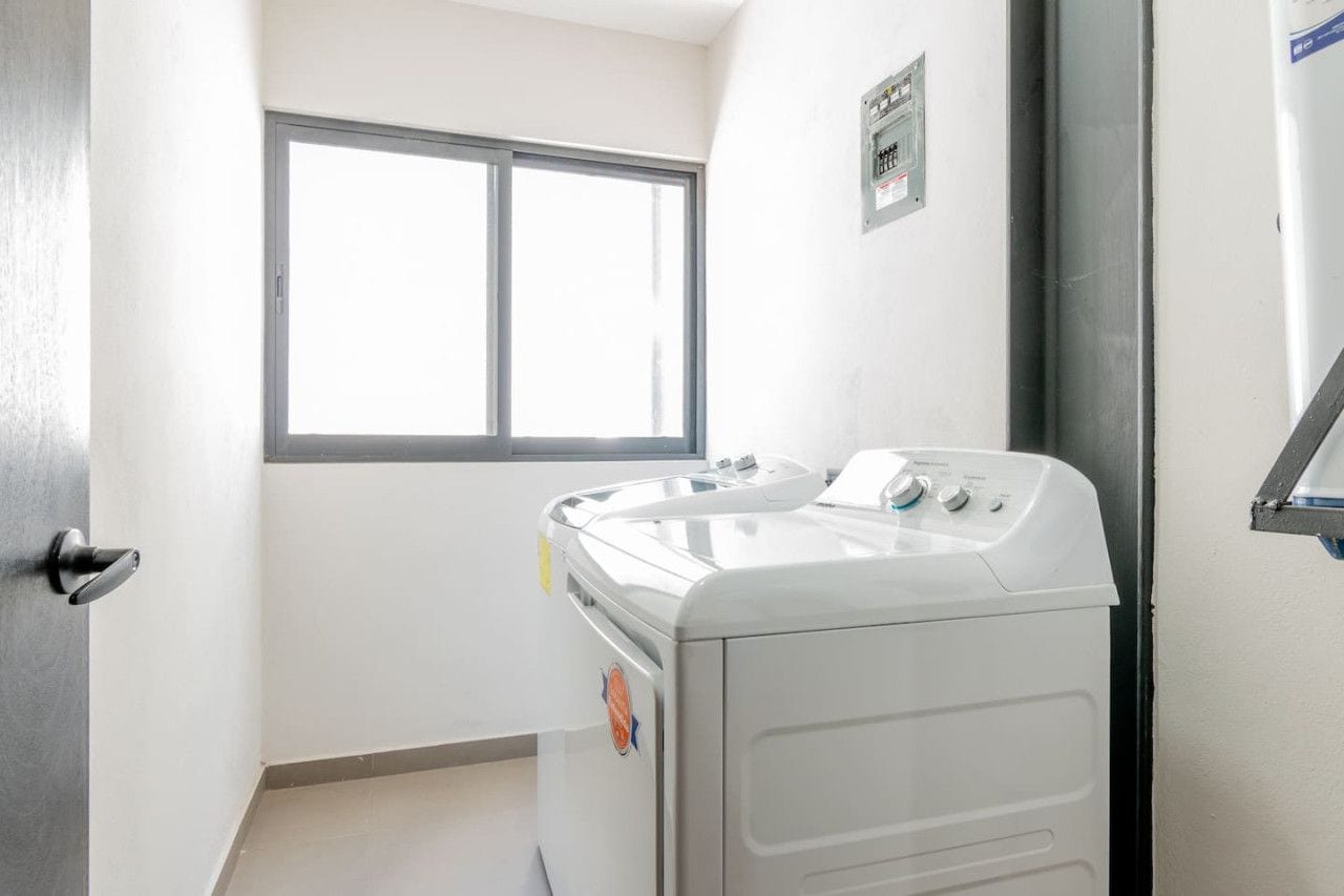 A laundry room with a washing machine and dryer, a window, and a door.