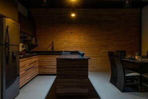 Cozinha moderna com parede de tijolos, armários de madeira e uma ilha central.