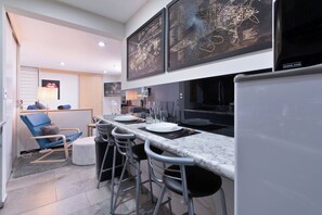 Une cuisine moderne dotée d’un plan de travail en marbre, de tabourets de bar et d’un coin repas.