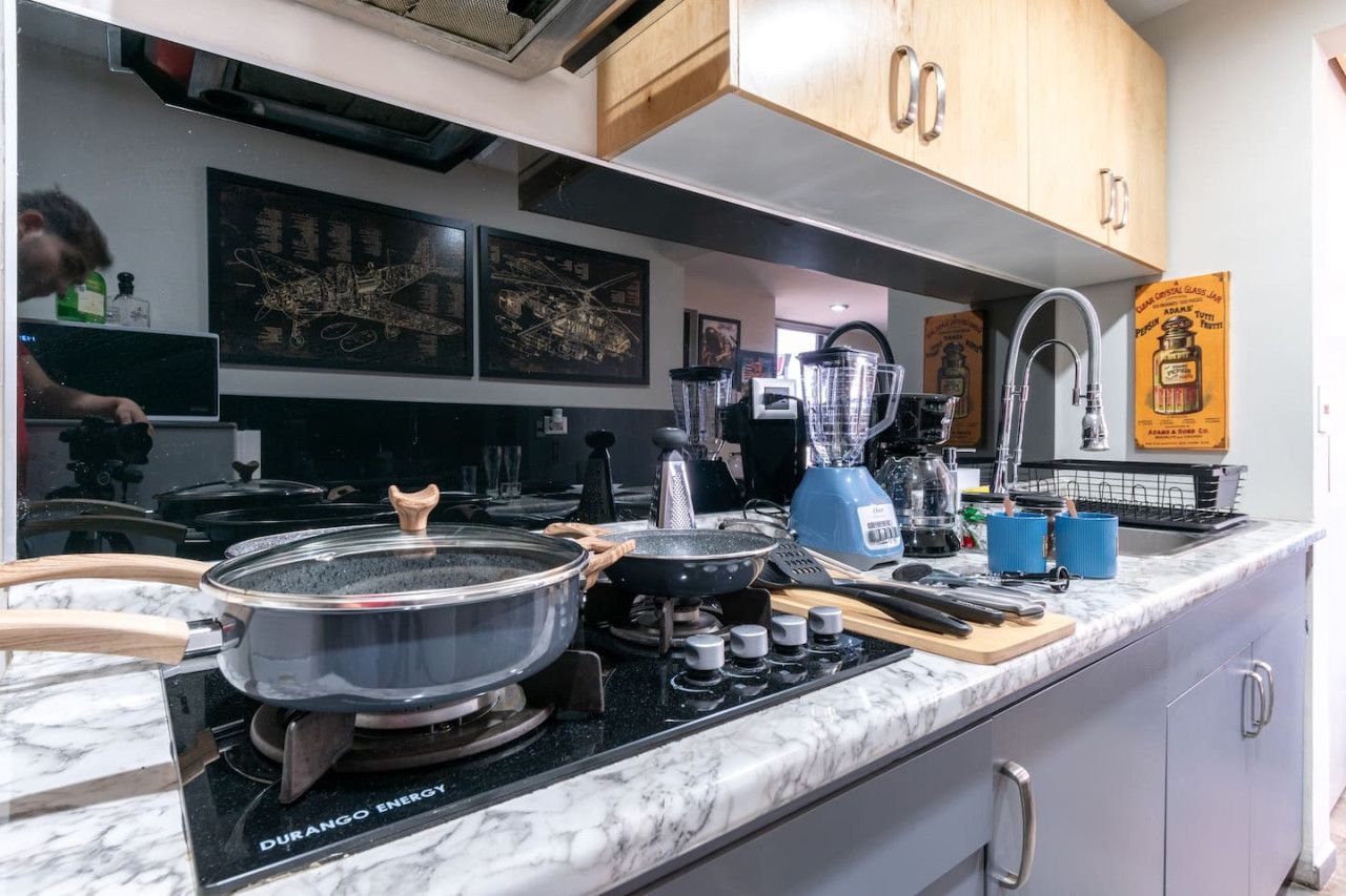 A kitchen with a gas stove, a blender, and a coffee machine.
