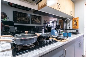 Una cocina con estufa a gas, licuadora y cafetera.