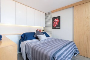 Une chambre à coucher moderne avec un lit, une table de chevet, une étagère fixée au mur et une affiche.