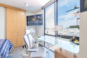 A modern hotel room with a large window, a desk, a chair, a bed, and a TV mounted on the wall. - Depa Ejecutivo Con Vista en Corazon de DGO (Durango)