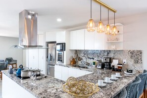 A modern kitchen with a central island, stainless steel appliances, and pendant lighting.