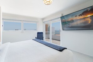 A hotel room with a large bed, a television on the wall, and a view of the city through the windows.