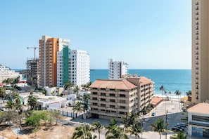 Un paysage urbain côtier avec de hauts immeubles, une plage et des palmiers.