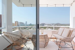 Varanda com mobiliário de vime, uma mesa redonda e vista para o horizonte urbano.