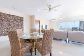A modern dining area with a round glass table, woven chairs, and a decorative wall panel. - Elegante Condo a una Cuadra del Mar en Nuevo Mazatlan (Mazatlán)