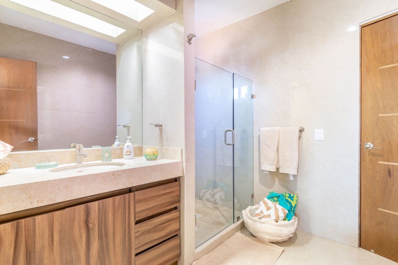 Un bagno moderno con cabina doccia in vetro, un mobile bagno in legno e uno specchio grande.