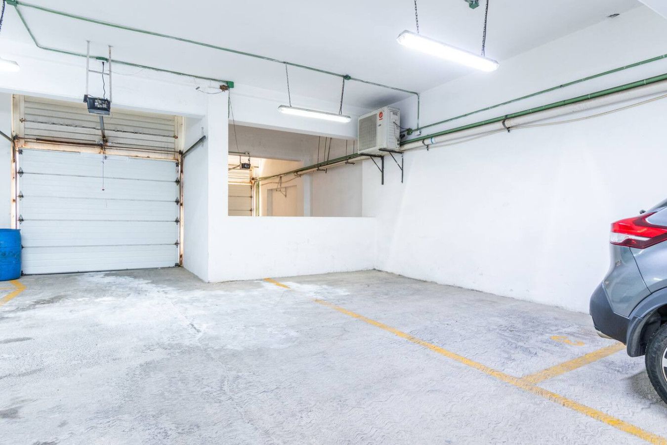 Eine Parkgarage mit Betonböden, einer geschlossenen Garagentür und einem abgestellten Auto.