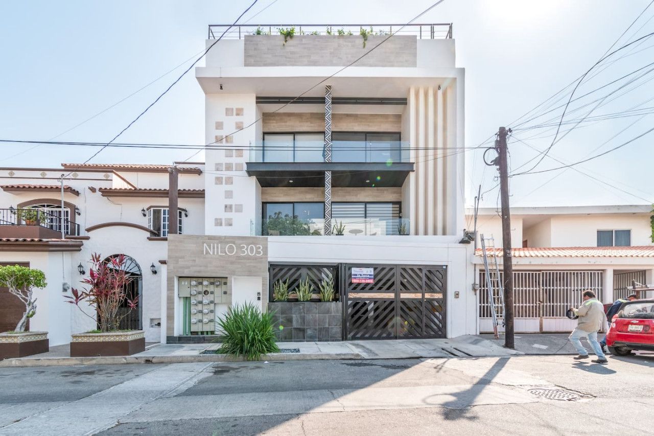 A modern building with a sign reading 'NILO 303' and a gated entrance.
