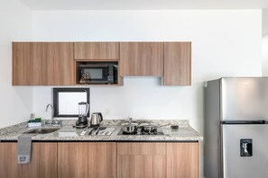 Une cuisine moderne avec des meubles en bois, un réfrigérateur en acier inoxydable, un four à micro-ondes, une cuisinière et un évier.