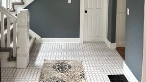 Una scala con ringhiere bianche e un lampadario nero che conduce a una porta con stipite bianco.