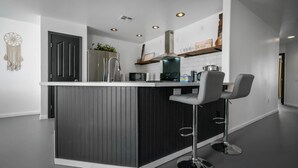 Een moderne keuken met een centraal eiland, roestvrijstalen apparatuur en barstoelen.