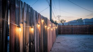 Een houten omheining met lichtjes, een metalen poort en een heldere lucht.