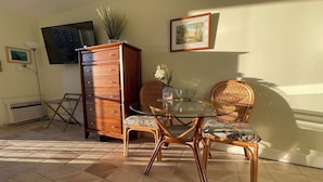 A dining area with a glass table, wicker chairs, a wooden cabinet, and a framed picture on the wall. - 🤩Great location🤩 8 guests~same floor (6)~ ✅ 2 studios ✅ free parking (Honolulu)