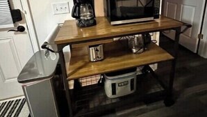 Eine kleine Küchenzeile mit Mikrowelle, Kaffeemaschine und Mülleimer.