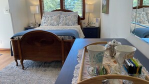 Un dormitorio ordenado con una cama de madera, una mesita de noche con lámparas y una bandeja con artículos de papelería.