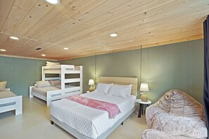 A bedroom with a bunk bed, a single bed, a bean bag chair, and bedside lamps.