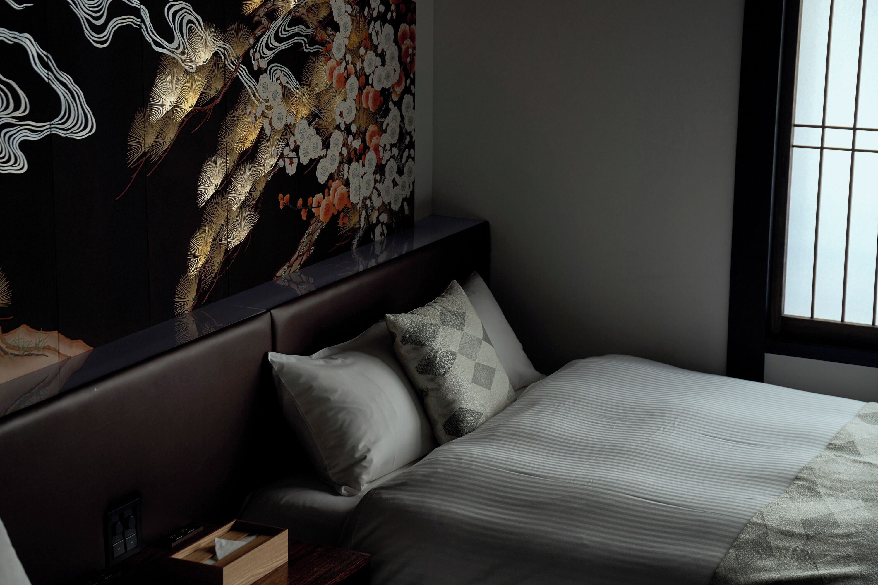 A bedroom with a bed, pillows, a nightstand, and a wall-mounted artwork.