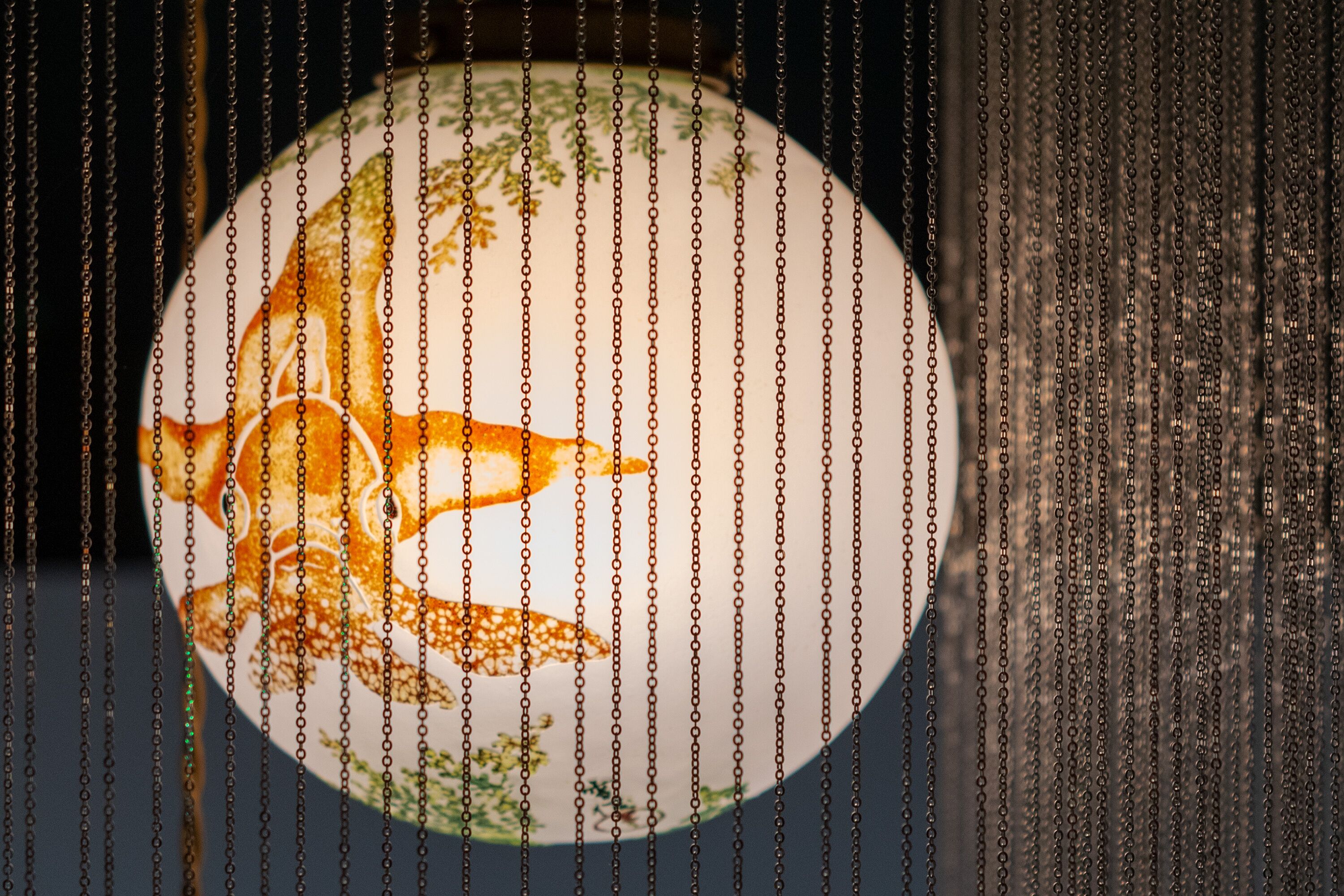 A circular object with a detailed design, partially obscured by hanging chains.