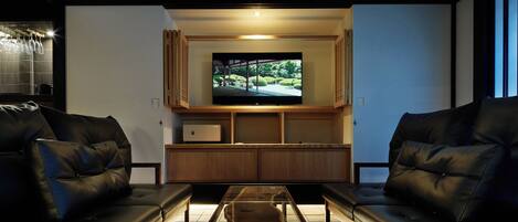 Una sala de estar moderna con un televisor de pantalla plana montado en un mueble de madera, sofás de cuero y una mesa de centro de vidrio.